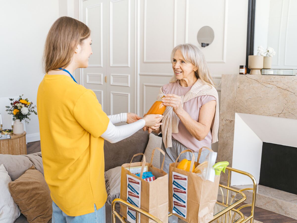 Carer smiling with a client while helping unpack shopping together at home