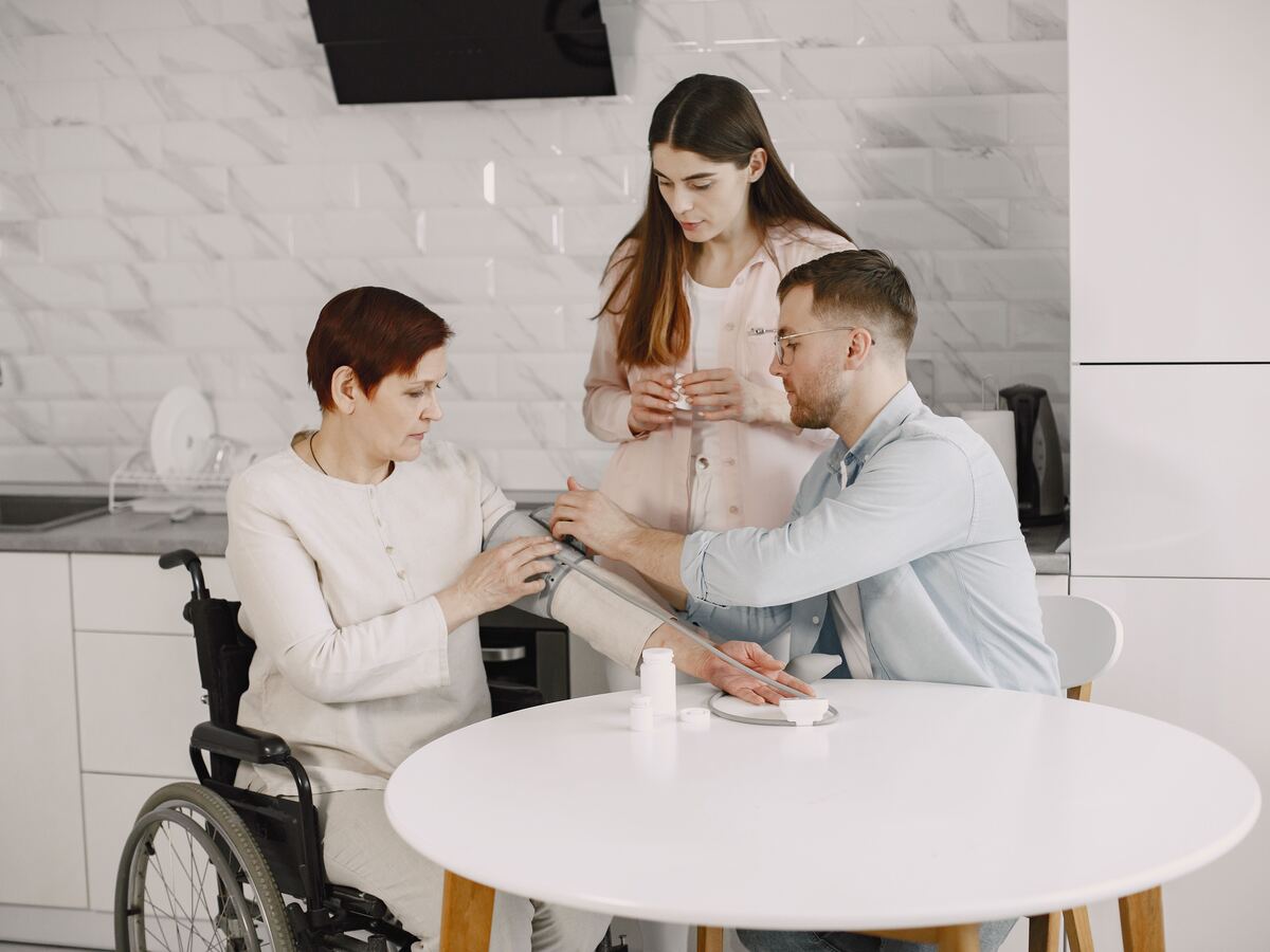 Carer supporting a client and family with medication and blood pressure monitoring at home